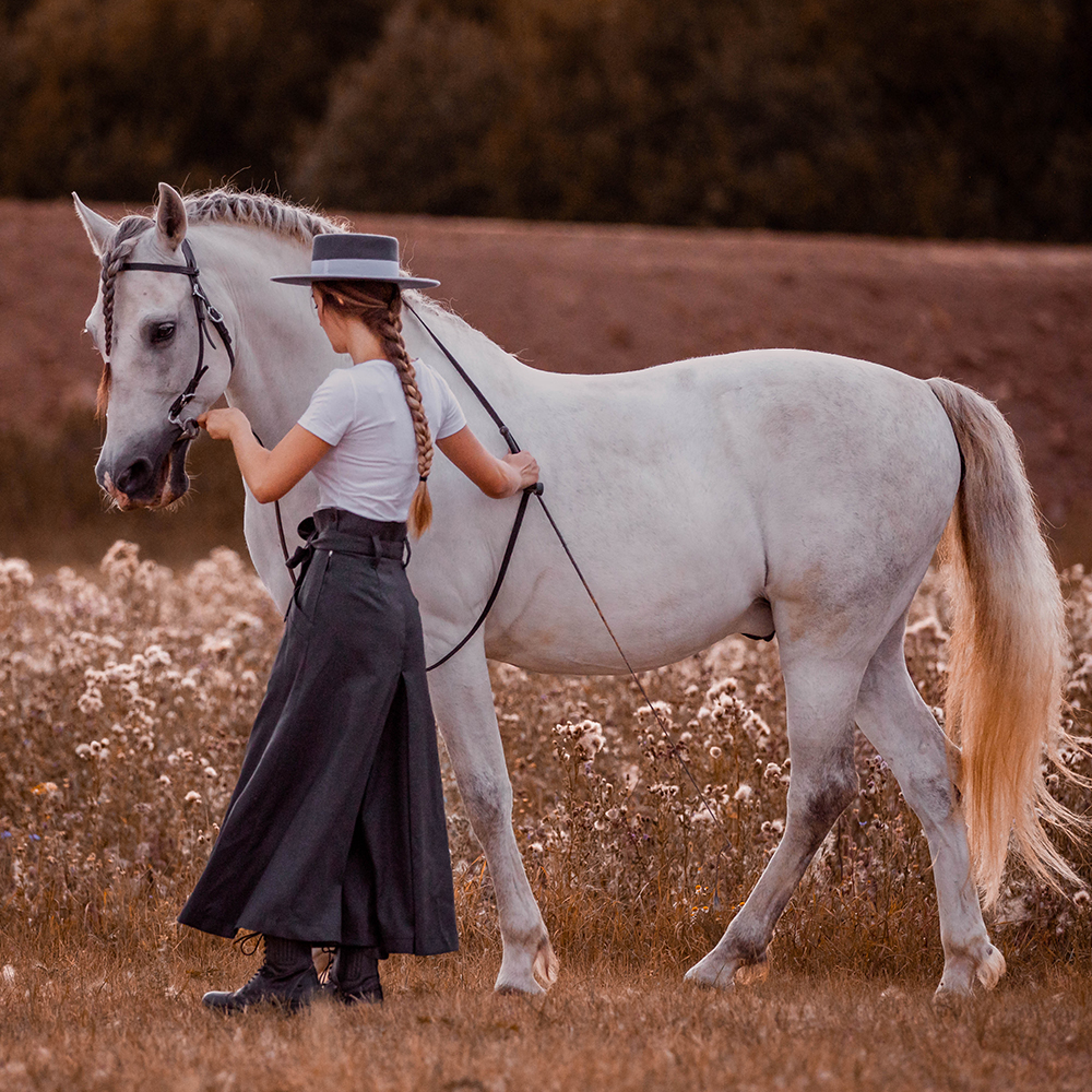 Reiterin mit ihrem weißen Pferd auf Wiese trägt Reitrock Hedy bei Picadera